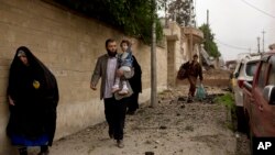 A toddler reaches for an overhead wire as she flees with her family during heavy fighting in the Yarmouk district of western Mosul, April 11, 2017. 