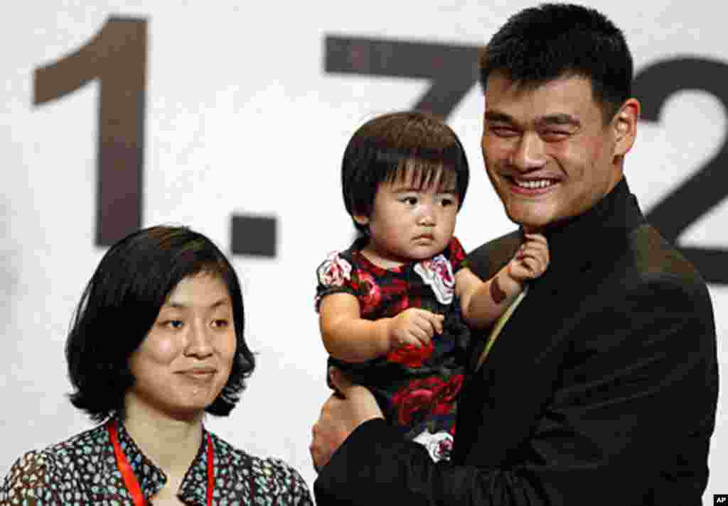 姚明在新闻发布会上怀抱女儿姚沁蕾，身旁站着妻子叶莉。