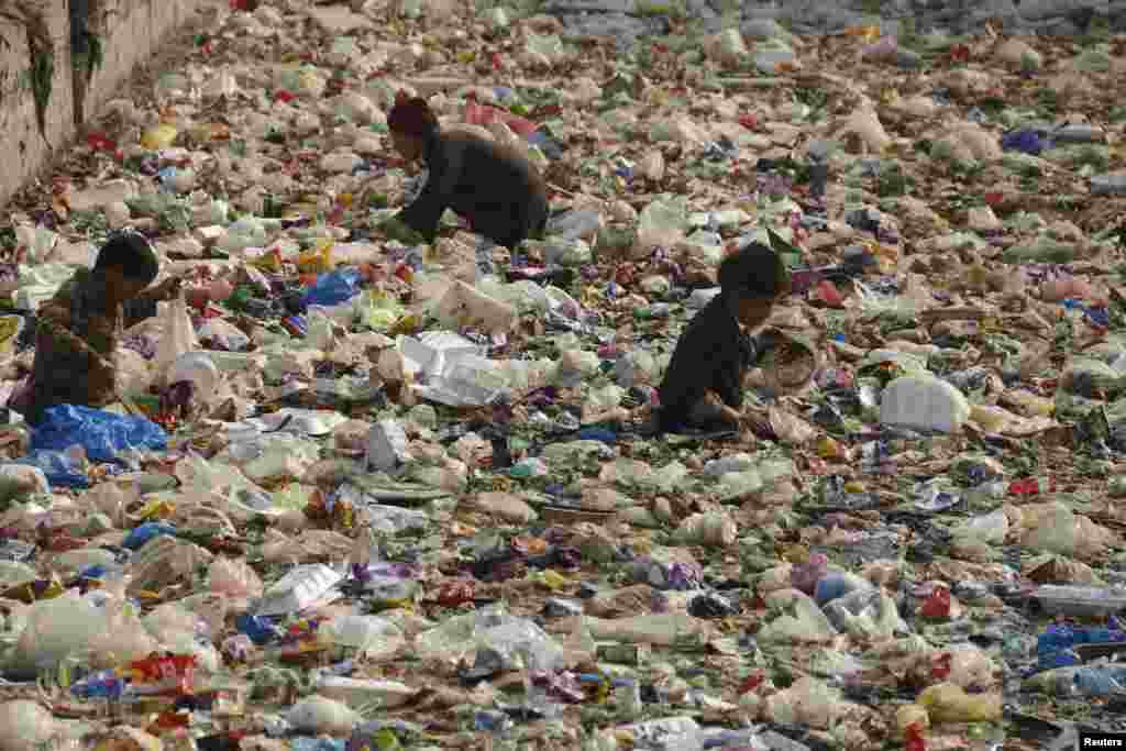 Anak-anak mencari plastik yang bisa didaur ulang di sebuah kanal di Peshawar, Pakistan.