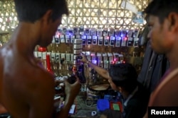 FILE - Rohingya Muslims charge their phone batteries in a shop at a refugee camp outside Sittwe, Myanmar, May 21, 2015.