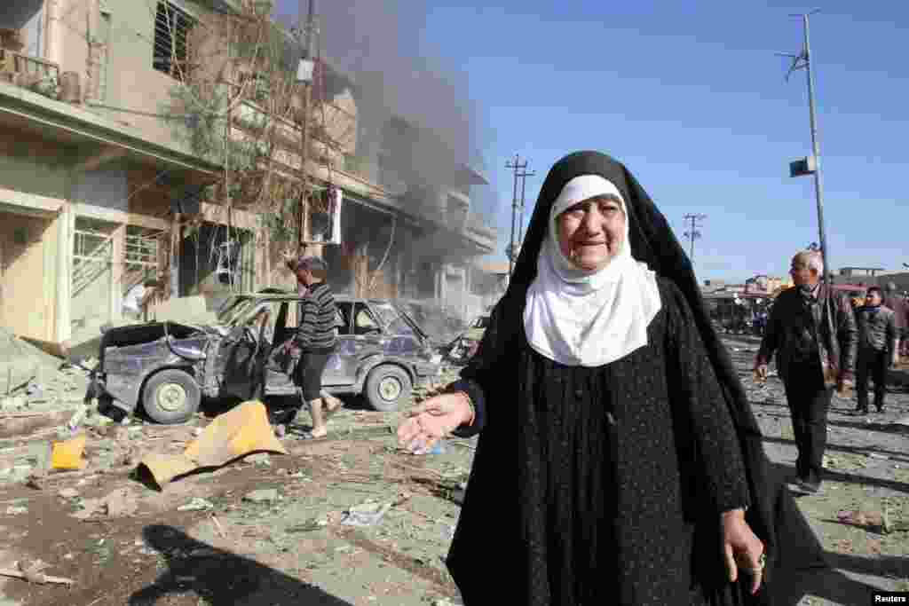 A woman stands near the site of bomb attack in Kirkuk, , Jan. 7, 2014.