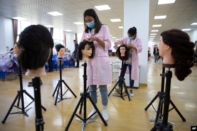 FILE - Students braid wigs during a class at the Peyzawat Training School in Peyzawat County in China's far west Xinjiang region, as seen during a state-organized tour for foreign media, April 19, 2021.