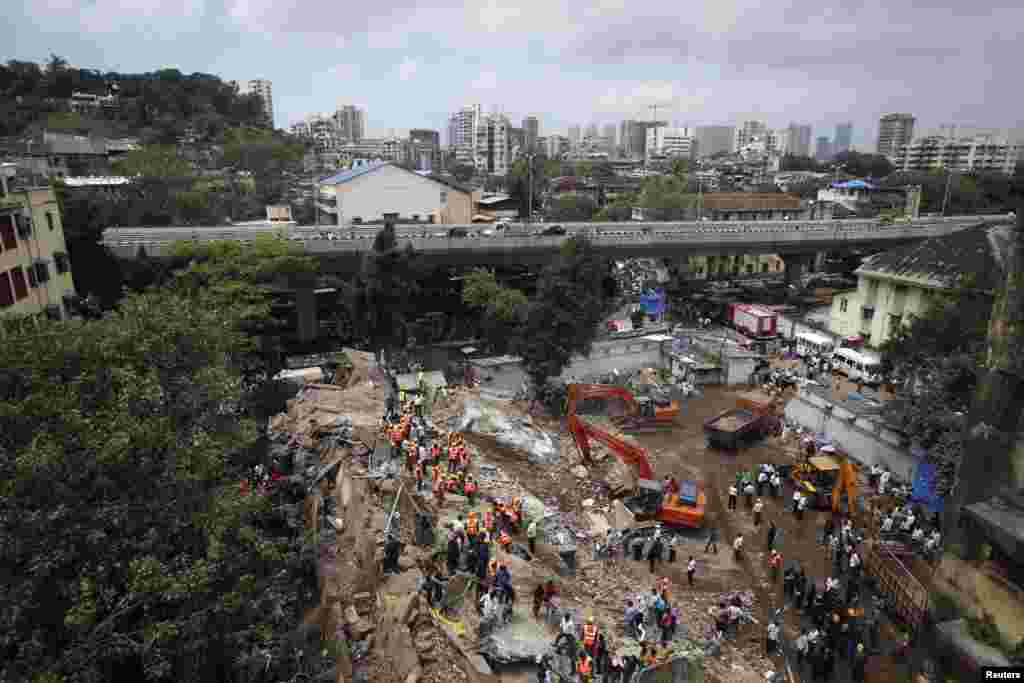 Para petugas penyelamat mencari para penyintas di lokasi gedung apartemen yang ambruk di Mumbai (27/9).