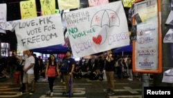 A poster with a drawing of an umbrella with the Chinese characters "peace" is displayed at a rally as protesters block the main road at Causeway Bay shopping district in Hong Kong September 30, 2014. As tensions subsided, weary protesters dozed or shelter