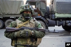 FILE - A Russia-backed rebel stands on guard during preparation for an exchange of prisoners in Donetsk, eastern Ukraine, Oct. 29, 2015.