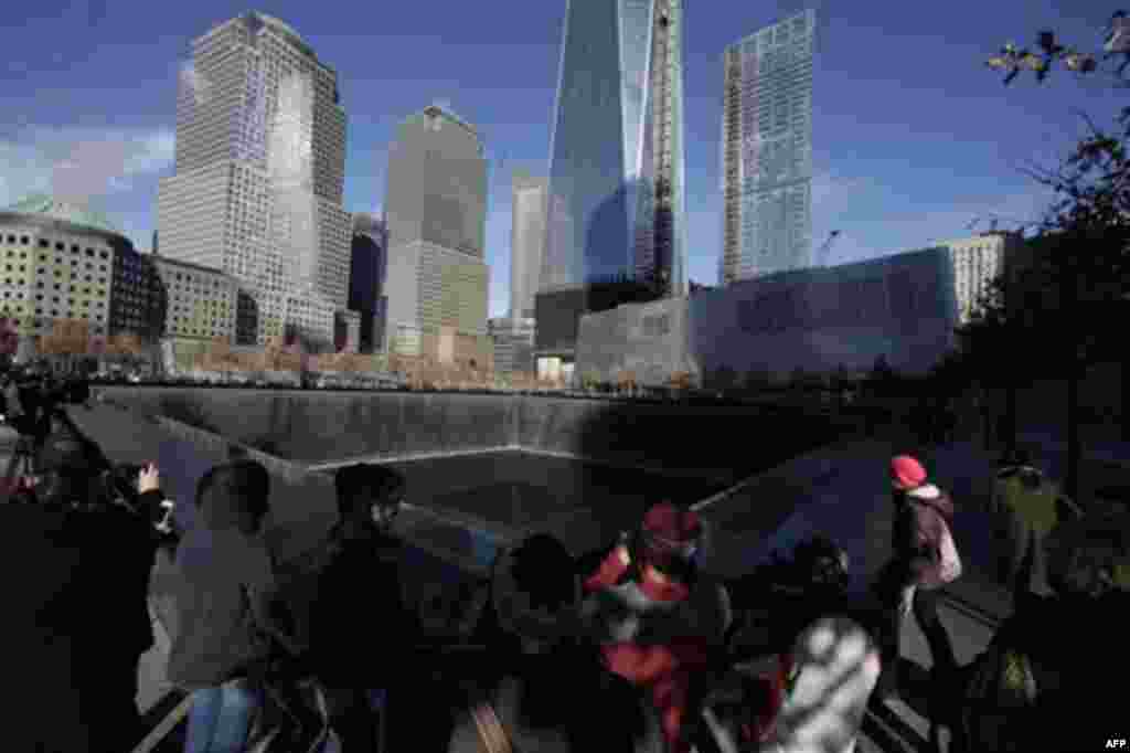 Visitors walk around the National September 11 Memorial, Thursday, Dec. 29, 2011 in New York. The memorial announced that it has had a million visitors since the site opened to the public in September. The museum entrance is at right. (AP Photo/Mark Lenni