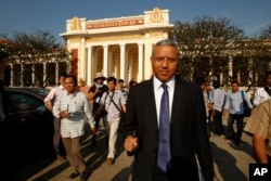 A U.N. Special Rapporteur on Human Rights, Surya Prasad Subedi, foreground, walks out from the Appeals Court after his attended a hearing of the case of 19 land rights activists and monks who were sentenced last November to 1 year in prison, in Phnom Penh, Cambodia, Thursday, Jan. 22, 2015. (AP Photo/Heng Sinith)