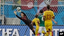 Mexico's goalkeeper Guillermo Ochoa, left, dives to make a save during the group A World Cup soccer match between Mexico and Cameroon in the Arena das Dunas in Natal, Brazil, June 13, 2014.
