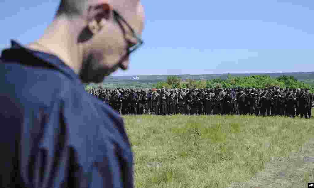 Ukrainian Prime Minister Arseniy Yatsenyuk stands in front of Ukrainian soldiers at a block post on the road at Slovyansk, Ukraine, Wednesday, May 7, 2014. Ukrainian military operations that began Monday to expunge pro-Russia forces from the city of Slovyansk were the interim government's most ambitious effort so far to quell weeks of unrest in Ukraine's mainly Russian-speaking east. (AP Photo/Andrew Kravchenko, Pool)