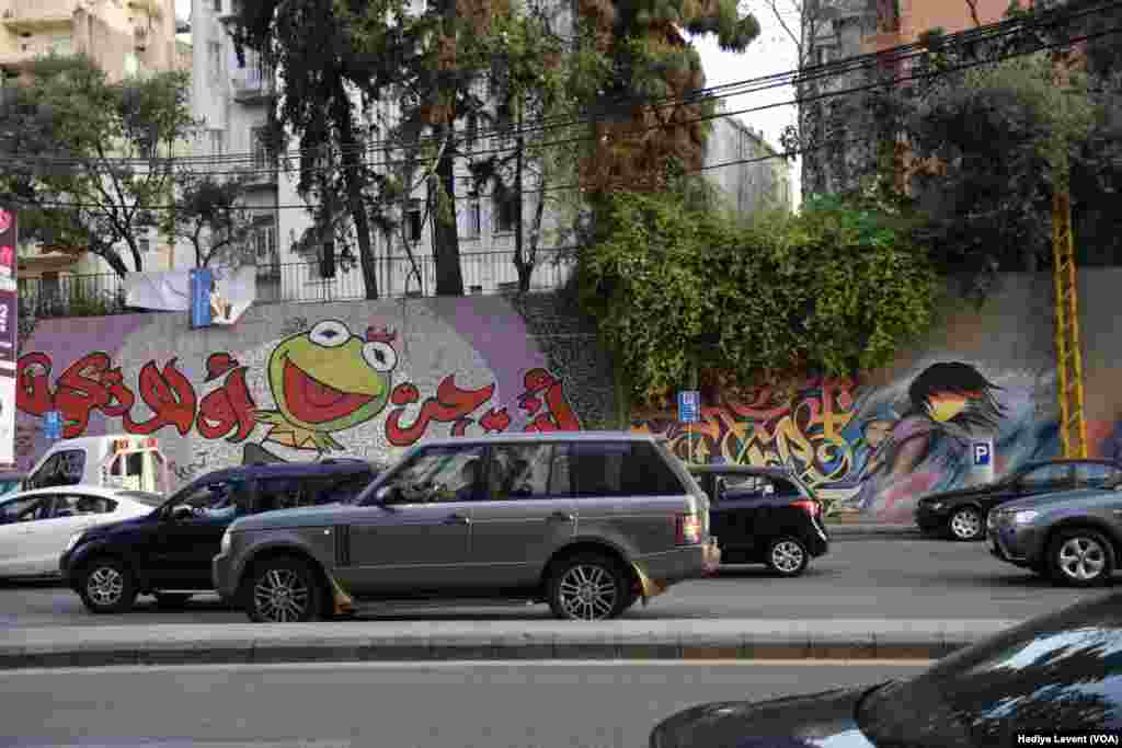 Yine Beyrut&rsquo;un en işlek caddelerinden birinin kenarındaki istinat duvarı graffiti sanatçılarının birbirinden farklı ve canlı resimlerinin doğal tuali olmuş. Bir tarafta olabildiğince canlı ve eğlenceli yeşil kurbağa, diğer tarafta bebeğini sırtına bağlamış yüzü belirsiz ve &ldquo;önemsiz&rdquo; bir kadın...