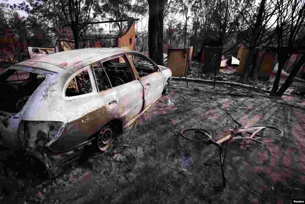 Houses can be seen behind a burnt-out car and bicycle after a fire destroyed them in the Blue Mountains suburb of Winmalee, west of Sydney, Oct. 21, 2013. 