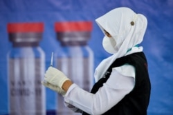 Seorang nakes menyiapkan vaksin COVID-19 Sinovac dalam vaksinasi massal di gedung konvensi di Banda Aceh pada 7 Juni 2021. (Foto: CHAIDEER MAHYUDDIN / AFP)