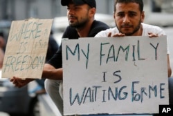 Migrants show placards outside of the railway station in Budapest, Hungary, Sept. 3, 2015.