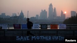 FILE - A commuter walks along Waterloo Bridge, which is being blocked by climate change activists, during the Extinction Rebellion protest in London, Apr. 17, 2019. 