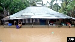 Warga berlindung di bawah atap sebuah rumah di distrik Paquite, Pemba, 29 April 2019, saat Topan Kenneth melanda wilayah utara Mozambik.
