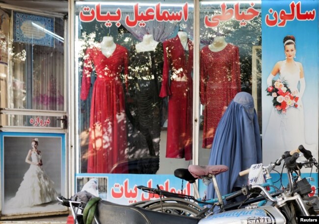 Seorang perempuan mengenakan burqa berjalan melewati toko pakaian perempuandengan manekin tanpa kepala yang dipajang di jendelanya, di Kabul, Afghanistan, 19 Oktober 2021. (Foto: Reuters)