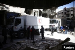 FILE - People are seen around Red Crescent aid truck in the besieged town of Douma, Eastern Ghouta, in Damascus, Syria, March 9, 2018.