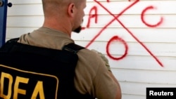 FILE - A Drug Enforcement Administration (DEA) agent marks a house after he searches it for survivors.