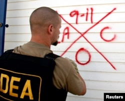 FILE - A Drug Enforcement Administration (DEA) agent marks a house after he searches it for survivors.