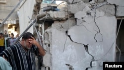 A Palestinian man reacts as he stands next to the wreckage of a house, which witnesses said was destroyed in an Israeli air strike that killed at least nine members from the al-Ghol family, in Rafah in the southern Gaza Strip, August 3, 2014.