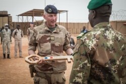FILE - French colonel Faivre hands over the symbolic key of Camp Barkhane to the Malian colonel during the handover ceremony of the Barkhane military base to the Malian army in Timbuktu, Dec. 14, 2021.