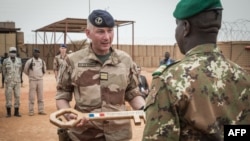 French colonel Faivre hands over the symbolic key of Camp Barkhane to the Malian colonel during the handover ceremony of the Barkhane military base to the Malian army in Timbuktu, Dec. 14, 2021.