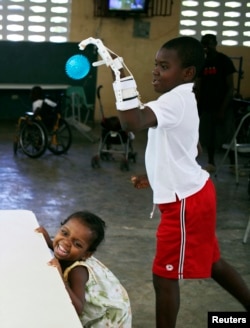 Stevenson Joseph (R), practices using a 3D-printed prosthetic hand at the orphanage where he lives in Santo, near Port-au-Prince, April 28, 2014.