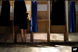 A woman prepares her ballot in a voting booth in the first round of parliamentary elections, in Lyon, central France, June 11, 2017. French voters went to the polls Sunday in the second round to choose lawmakers in the lower house of parliament.