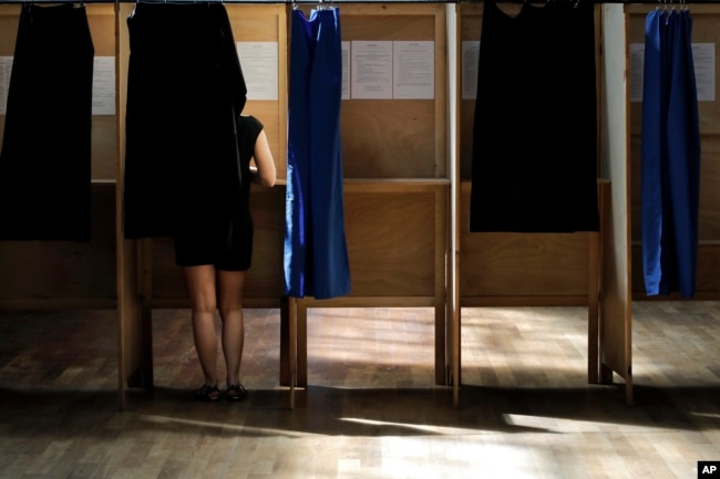 A woman prepares her ballot in a voting booth in the first round of parliamentary elections, in Lyon, central France, June 11, 2017. French voters went to the polls Sunday in the second round to choose lawmakers in the lower house of parliament.