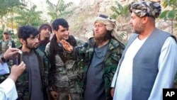 FILE - An Islamic State fighter, second right, speaks to a journalist after he surrendered to government security forces in the Jawzjan province, north of Kabul, Afghanistan, Wednesday, Aug. 1, 2018.