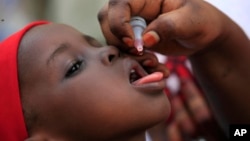 FILE - An unidentified health official administers a polio vaccine to a child in Kawo Kano, Nigeria.