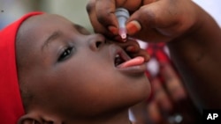 FILE - An unidentified health official administers a polio vaccine to a child in Kawo Kano, Nigeria, April. 13, 2014.