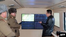 这张照片拍摄于2022年1月11日，由朝鲜官方的朝中社于2022年1月12日发布。照片显示，朝鲜领导人金正恩(右)在观察国家媒体所说的超高音速导弹发射时与军方官员交谈。（法新社）