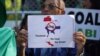 A man holds up a sign protesting against a proposed coal-fired plant on Thailand's coast, in Bangkok, Thailand, Feb. 17, 2017. The Thai government has put on hold construction of the plant near the pristine beaches on the Andaman Sea.