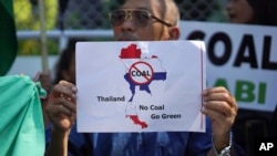 A man holds up a sign protesting against a proposed coal-fired plant on Thailand's coast, in Bangkok, Thailand, Feb. 17, 2017. The Thai government has put on hold construction of the plant near the pristine beaches on the Andaman Sea.