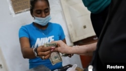 Un cliente paga su compra con billetes de dólares estadounidenses en un mercado de frutas y verduras en Caracas, el 22 de diciembre de 2020.