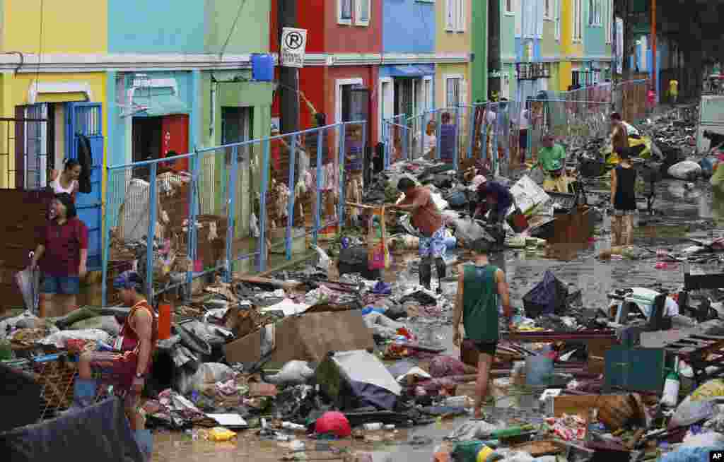 Residents look for their belongings after heavy rains and strong winds brought by a tropical storm flooded Marikina city, east of Manila, Philippines.