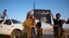 Iraqi Shiite militia fighters hold the Islamic State flag as they celebrate after breaking the siege of Amerli by Islamic State militants, Sept. 1, 2014. 
