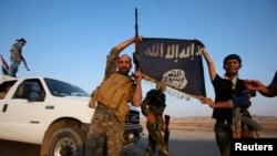 Iraqi Shiite militia fighters hold the Islamic State flag as they celebrate after breaking the siege of Amerli by Islamic State militants, Sept. 1, 2014. 