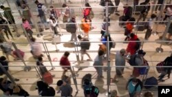 Plexiglass separates travelers to prevent the spread of COVID-19 as they make their way through the line to clear security at Love Field in Dallas, Dec. 31, 2021.