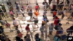Plexiglass separates travelers to prevent the spread of COVID-19 as they make their way through the line to clear security at Love Field in Dallas, Dec. 31, 2021.