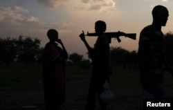 FILE _ An armed man and a woman from the Nuer tribe talk in South Sudan, July 24, 2013.