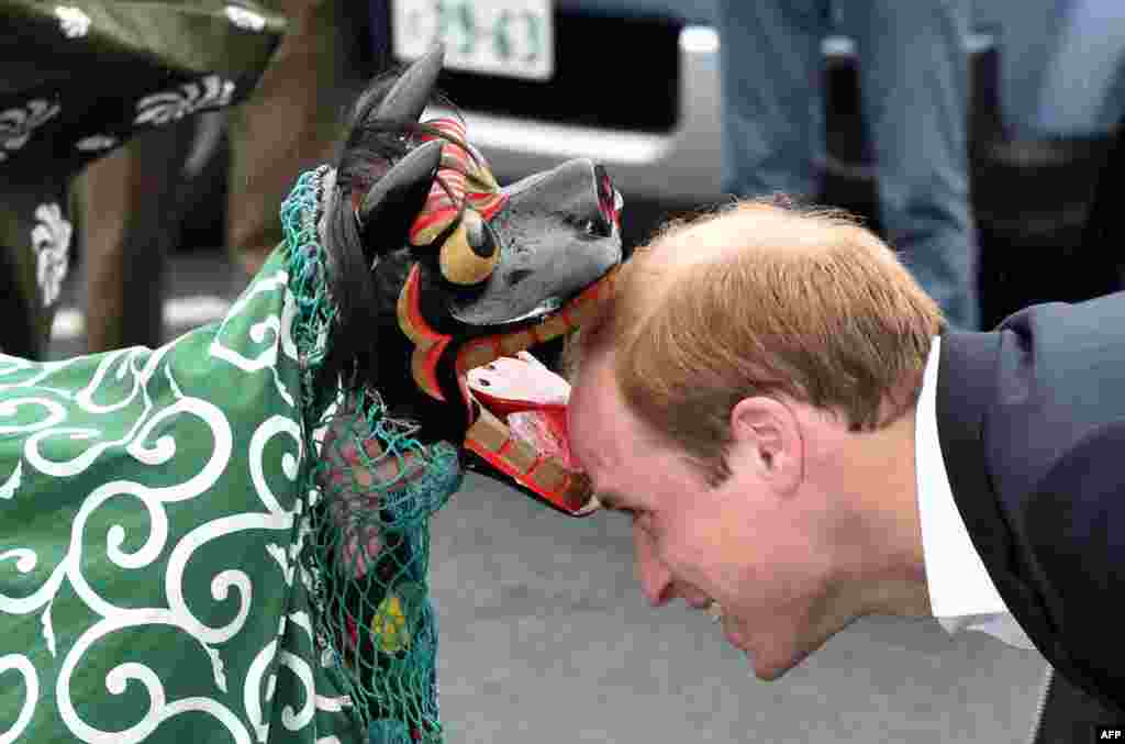 Britain&#39;s Prince William (R), Duke of Cambridge, is greeted by a lion dance during his visit to the Chime of Hope Shopping Centre in Onagawa, Miyagi prefecture, Japan.