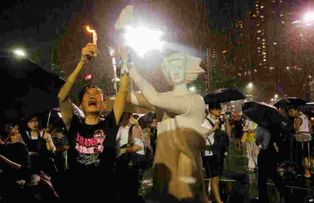 Seorang pria memegang lilin di depan replika Dewi Demokrasi di Victoria Park, Hong Kong (4/6), dalam peringatan 24 tahun tragedi Tiananmen. (AP/Vincent Yu)