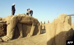 Pekerja Irak membersihkan patung banteng bersayap di sebuah situs arkeologi di Nimrud dalam foto tahun 2001 ini. Militan ISIS membuldoser dan menjarah situs kuno tersebut, kata pemerintah Irak, 6 Maret 2015. (Foto: AFP)