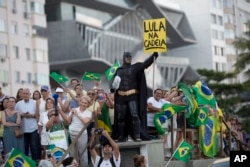 A demonstrator dressed as Batman holds a sign that reads in Portuguese "Lula in Prison" during a protest against former President Luiz Inacio Lula da Silva on Copacabana beach, in Rio de Janeiro, Brazil, Jan. 23, 2018.