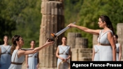 Greek actress Xanthi Georgiou, playing the role of the High Priestess, lights the torch during the flame lighting ceremony for the Beijing 2022 Winter Olympics at the Ancient Olympia archeological site, birthplace of the ancient Olympics in southern Greece, Oct. 18, 2021. 