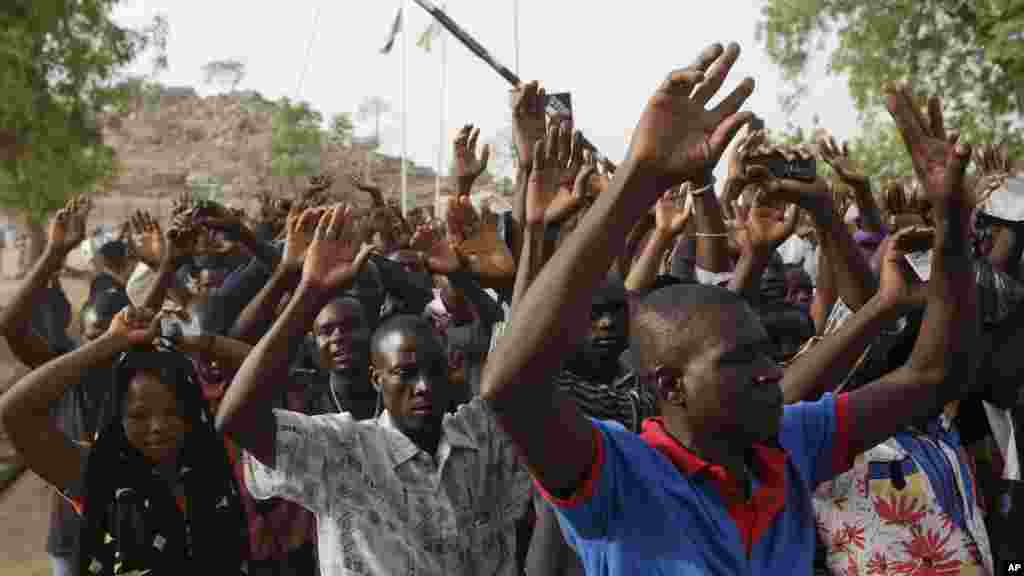 Mains levées, des personnes déplacées suite aux attaques des combattants islamistes s&rsquo;apprêtent à passer au point de contrôle de la sécurité avant de voter, à Yola, au Nigeria, samedi 28 mars 2015.