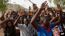 Mains levées, des personnes déplacées suite aux attaques des combattants islamistes s’apprêtent à passer au point de contrôle de la sécurité avant de voter, à Yola, au Nigeria, samedi 28 mars 2015. 