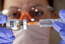 Seorang tenaga medis memegang botol kecil dengan stiker bertuliskan "Vaksin Covid-19" dan suntikan dalam foto ilustrasi, 10 April 2020. (Foto: Reuters)